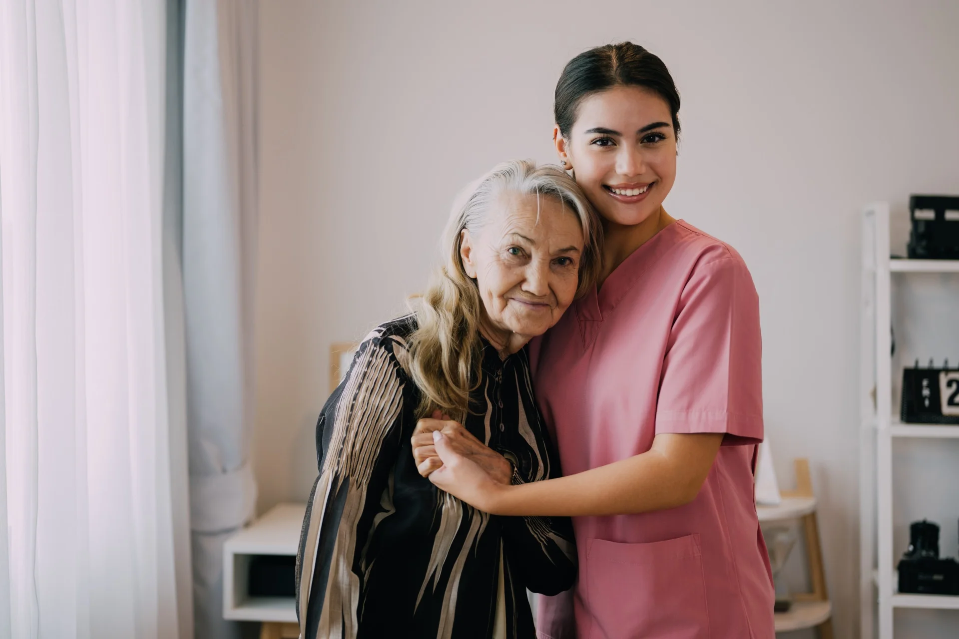 happy-caregiver-and-senior-patient-smiling-and-loo-2023-02-23-23-11-38-utc.webp